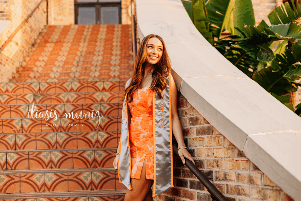 "Graduate sitting on colorful tiled staircase at UTRGV"
